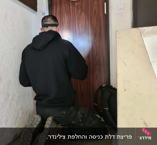 אדם כורע מול דלת עם כלי עבודה
